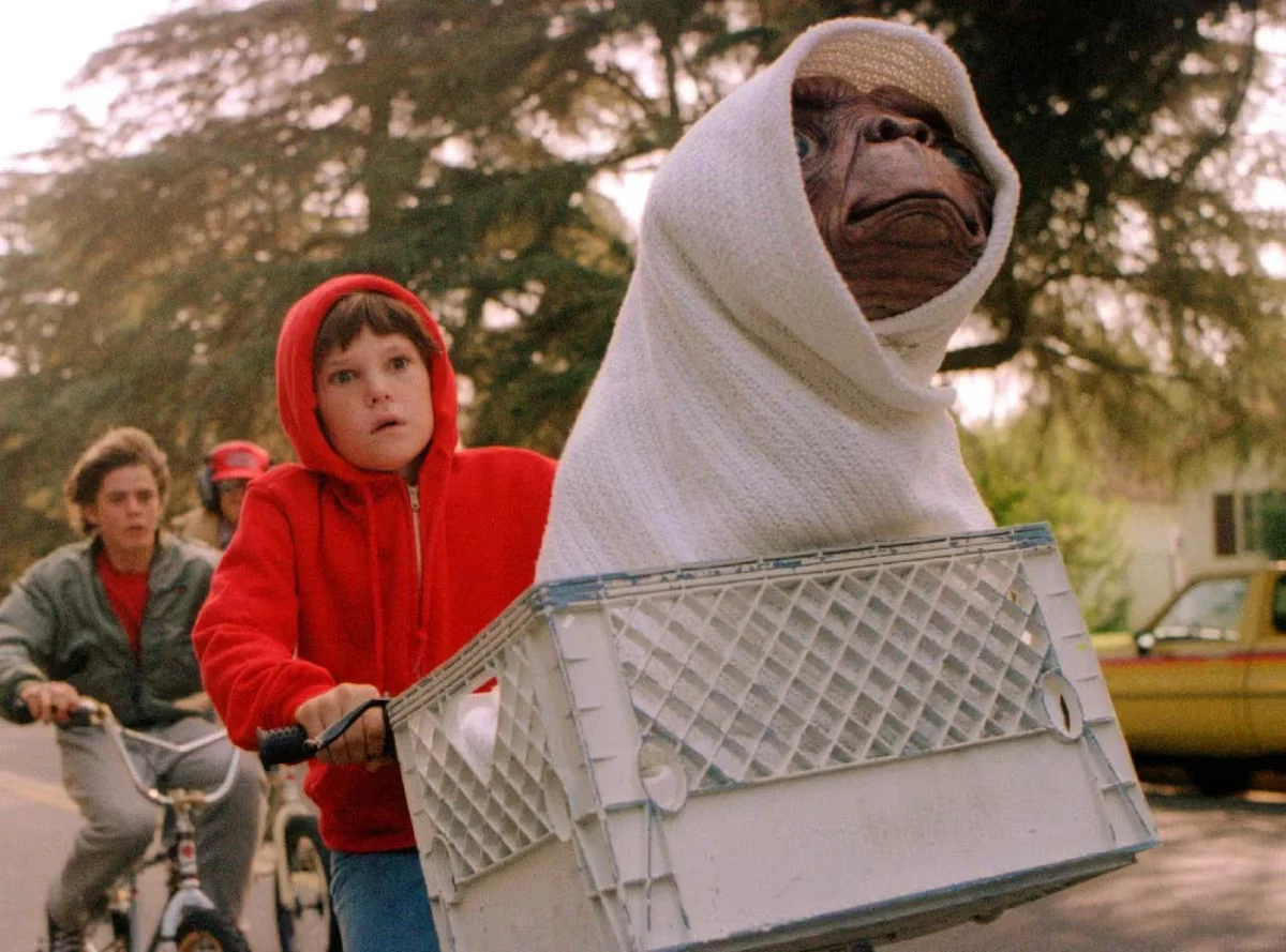 O Extraterrestre” mostra Elliott pedalando com E.T. escondido em uma cesta de bicicleta durante perseguição.