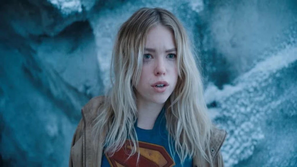 Cena do filme Supergirl mostra a heroína em ambiente gelado usando camiseta com símbolo clássico.