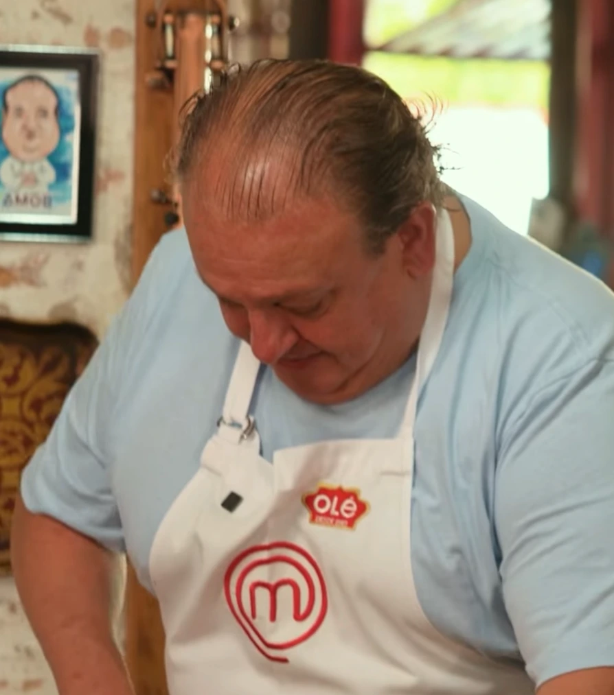 Chef Erick Jacquin usando avental da Olé enquanto cozinha em ambiente rústico.
