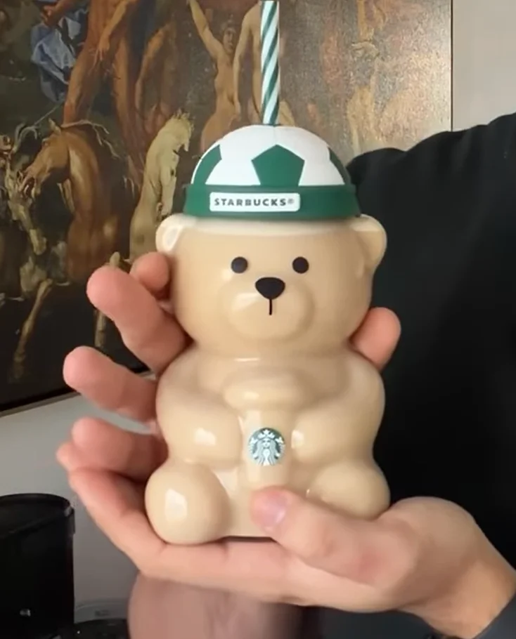Close-up das mãos de uma pessoa segurando o copo de urso da Starbucks.
