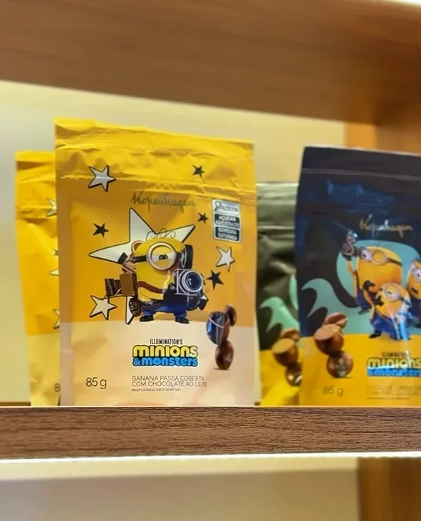 Embalagens de chocolates Minions da Kopenhagen expostas em prateleira com destaque para pouchs amarelos temáticos.