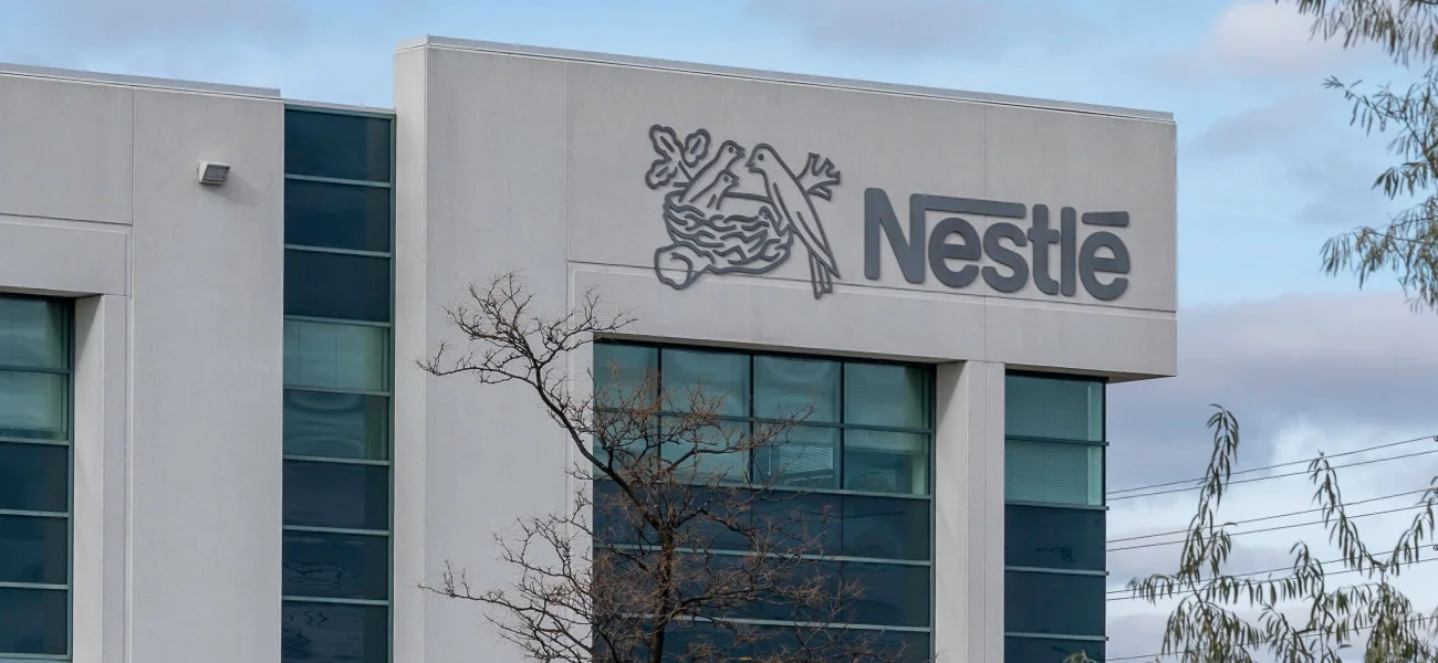Fachada de prédio corporativo da Nestlé com logo da marca em destaque na parede externa.