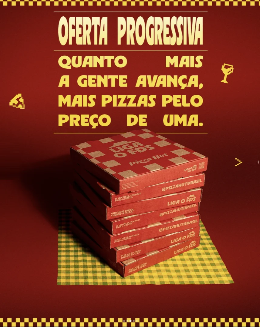 Pilha de caixas da Pizza Hut em cenário vermelho com texto sobre oferta progressiva de pizzas pelo preço de uma.