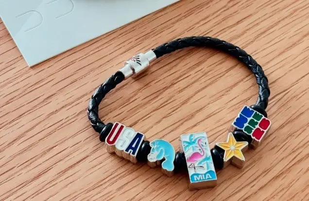 Pulseira preta da Copa com pingentes coloridos inspirados em Miami e símbolos do torneio.