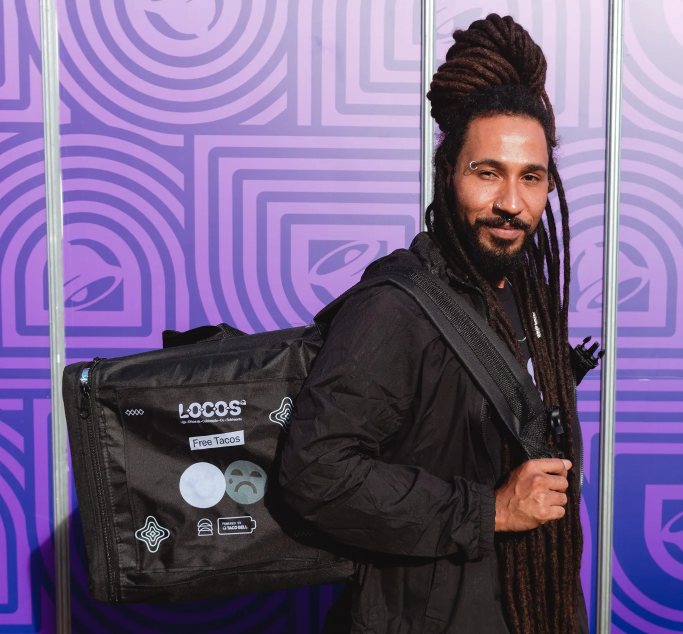 Homem com dreadlocks posa com mochila de entregas personalizada da campanha Locos do Taco Bell.