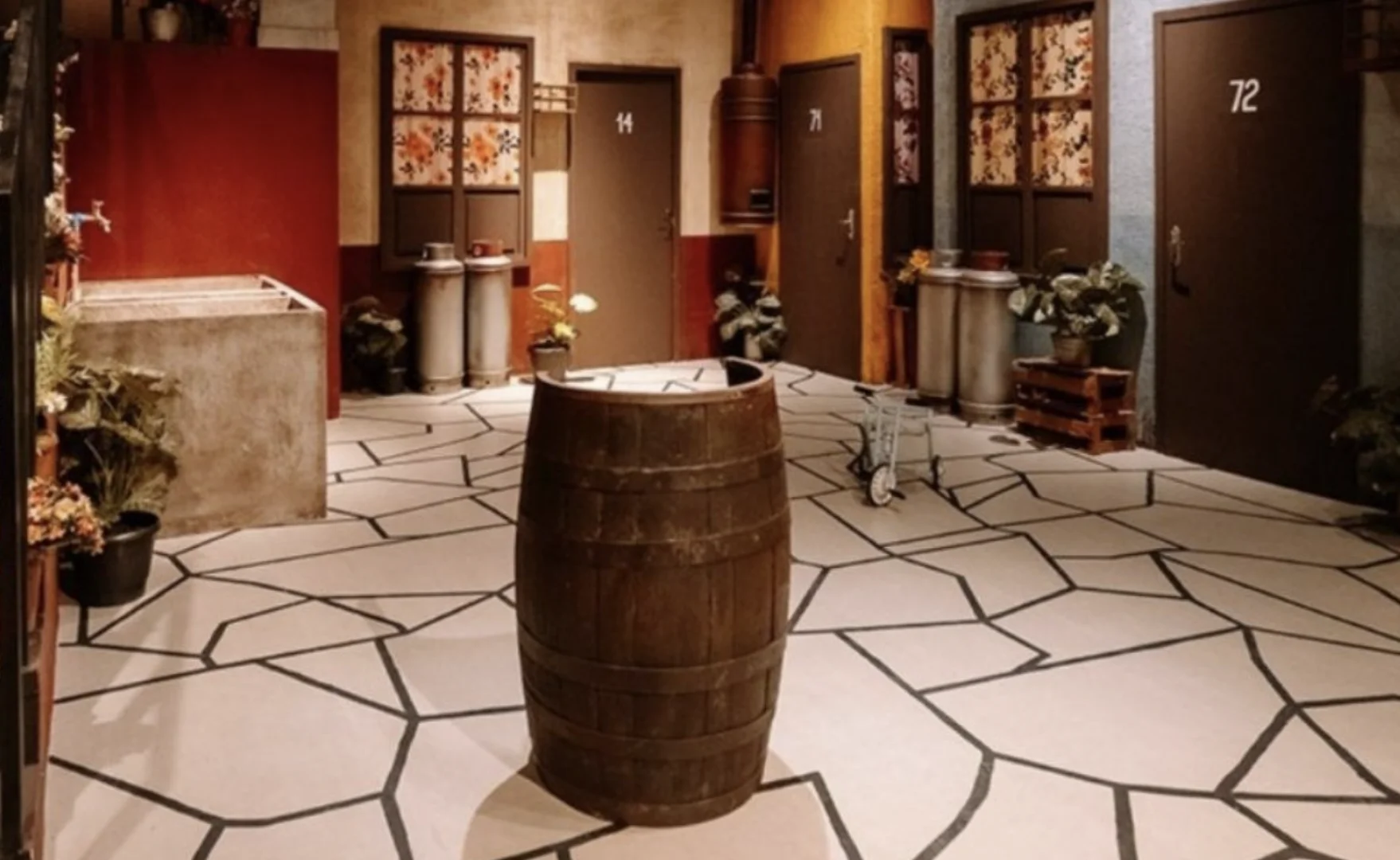 Cenário inspirado na vila do Chaves com barril no centro, portas numeradas e ambientação temática da série mexicana.