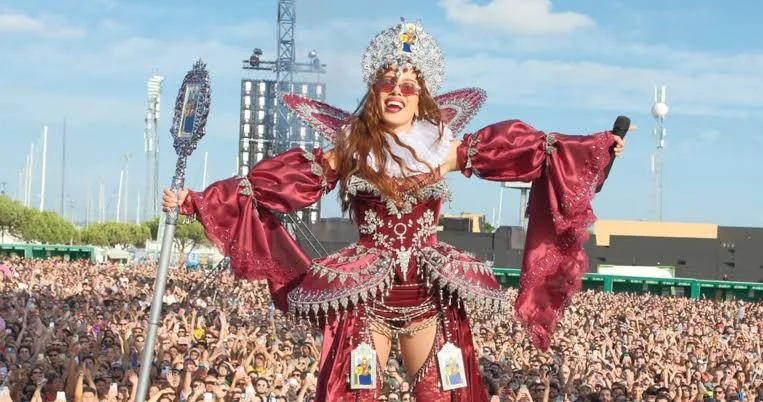Anitta durante os Ensaios da Anitta em Portugal, usando figurino vermelho e segurando um microfone diante de uma multidão.