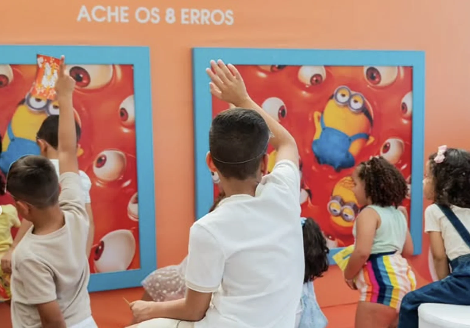 Crianças participam do desafio de encontrar diferenças em painel da experiência Minions & Monstros.