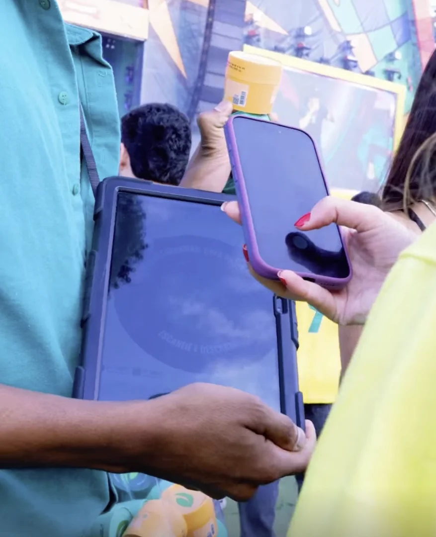 Participantes escaneiam QR Code da ativação da Herbíssimo para receber produtos gratuitos durante evento em São Paulo.