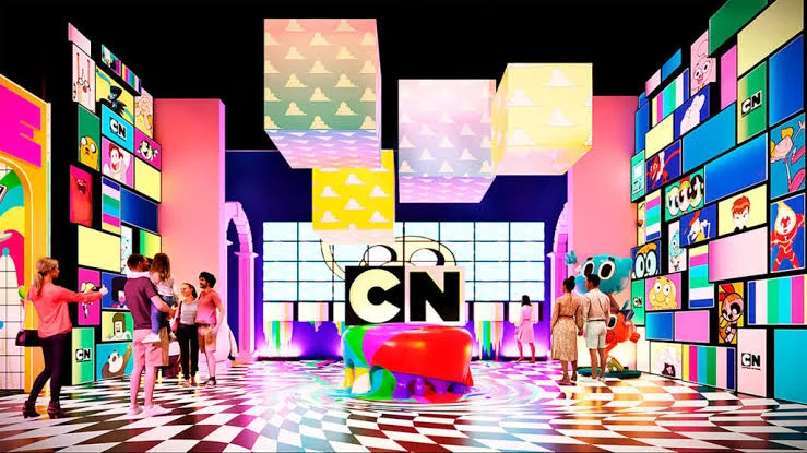 Ambiente imersivo do Cartoon Network com painéis coloridos, personagens clássicos e visitantes explorando a atração.