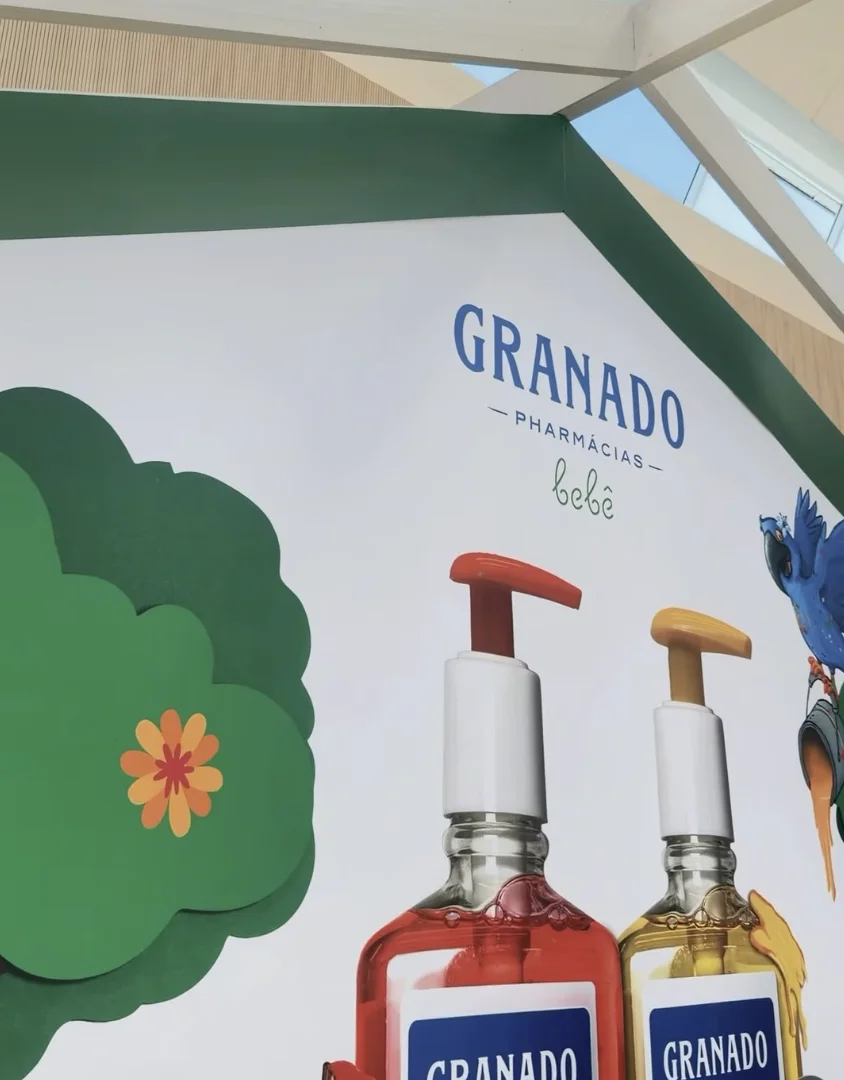 Painel decorado da Granado Bebê com ilustrações, árvores cenográficas e frascos gigantes da linha infantil.