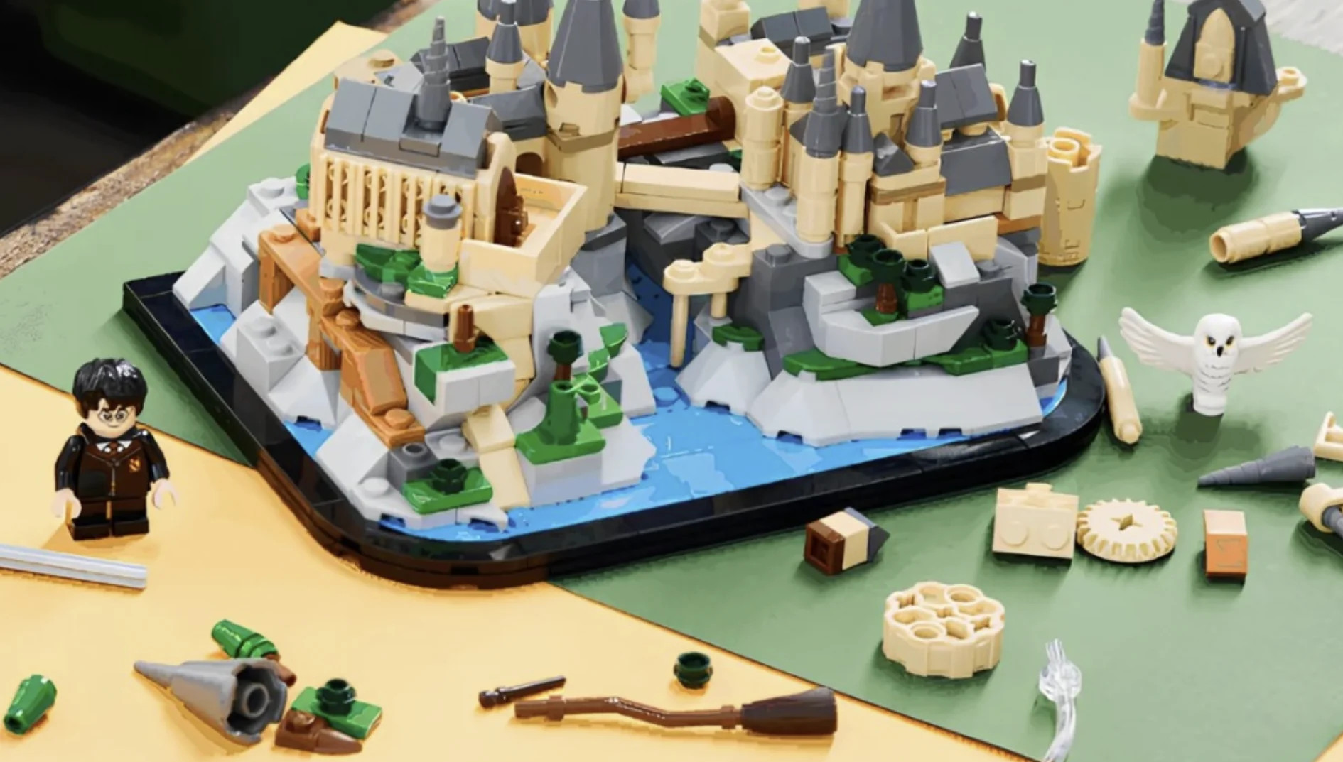 Mini Castelo de Hogwarts da LEGO parcialmente montado, cercado por peças, acessórios e minifigura de Harry Potter durante a montagem.