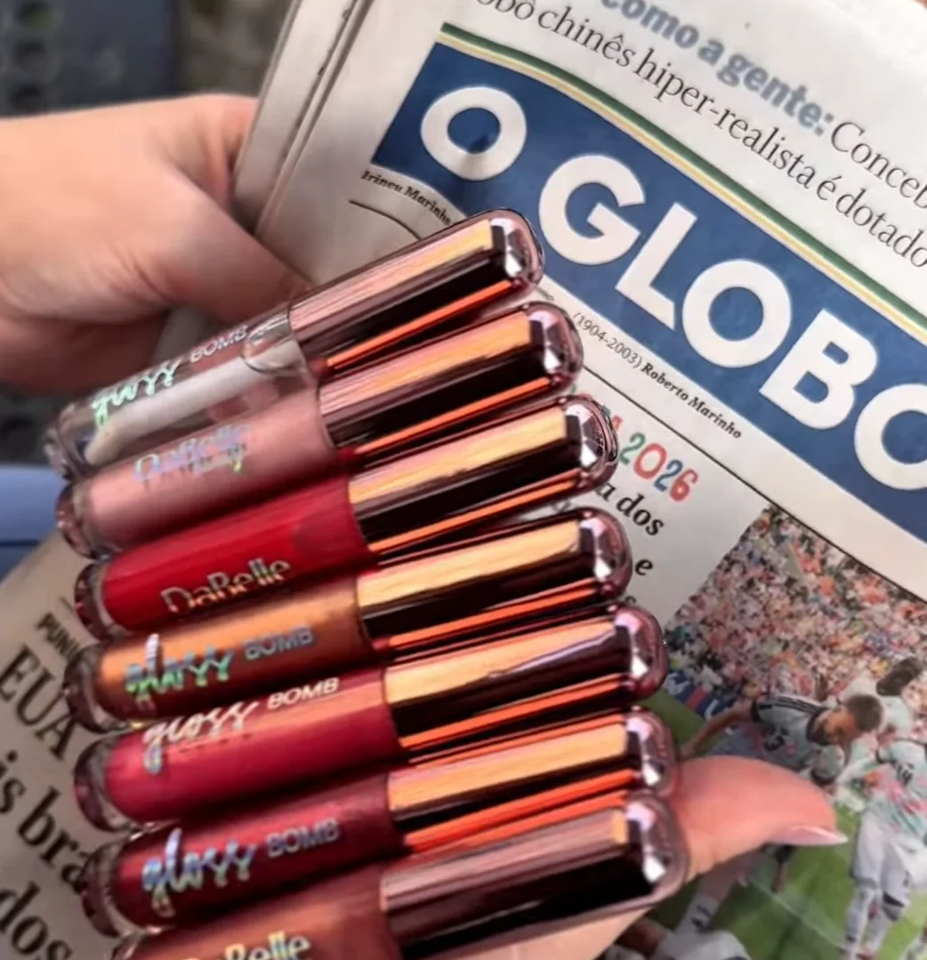 Linha de glosses DaBelle posicionada sobre exemplar do jornal O Globo.