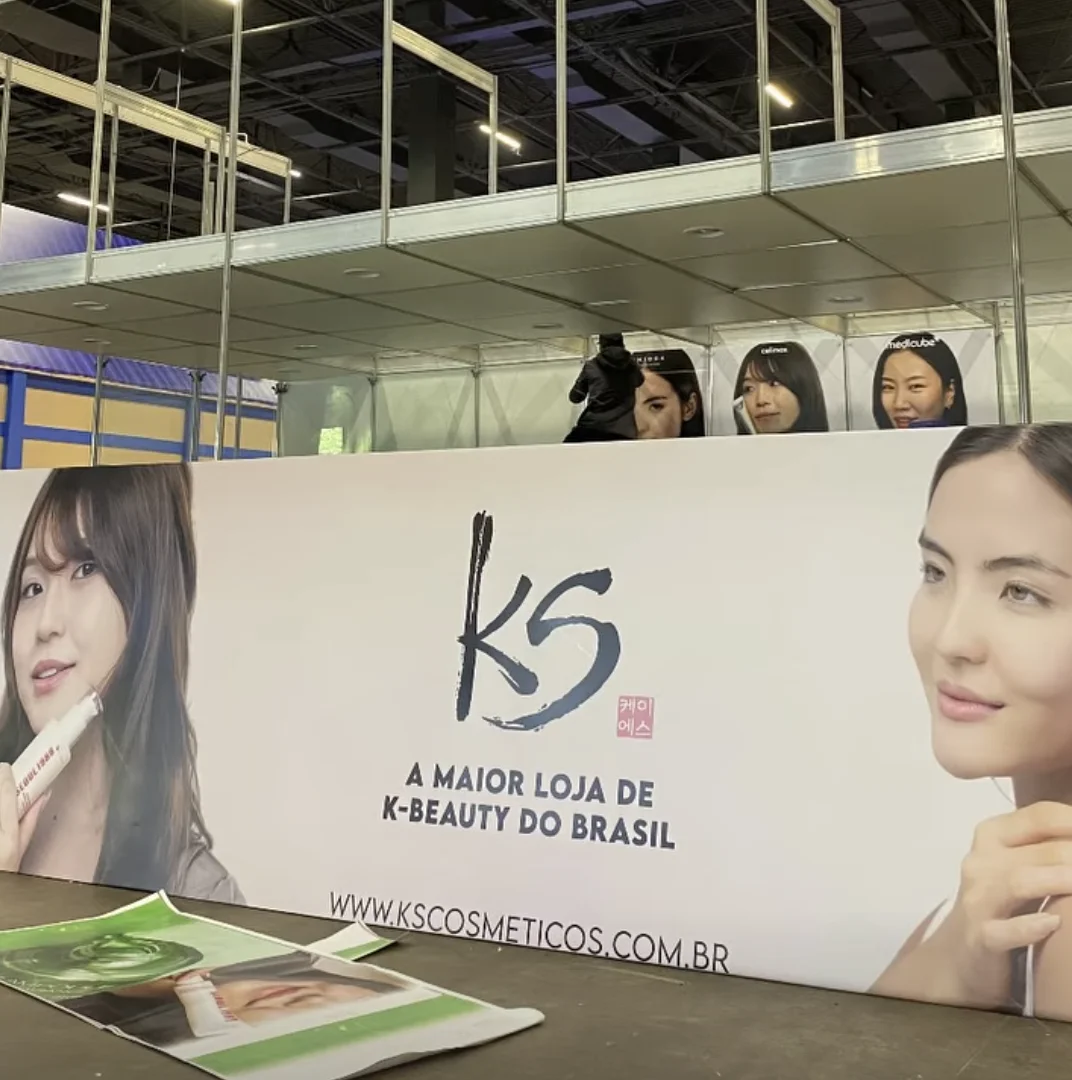 Estande da KS Cosméticos em montagem para o Festival do Japão, com painéis de marcas de K-Beauty e identidade visual da empresa.