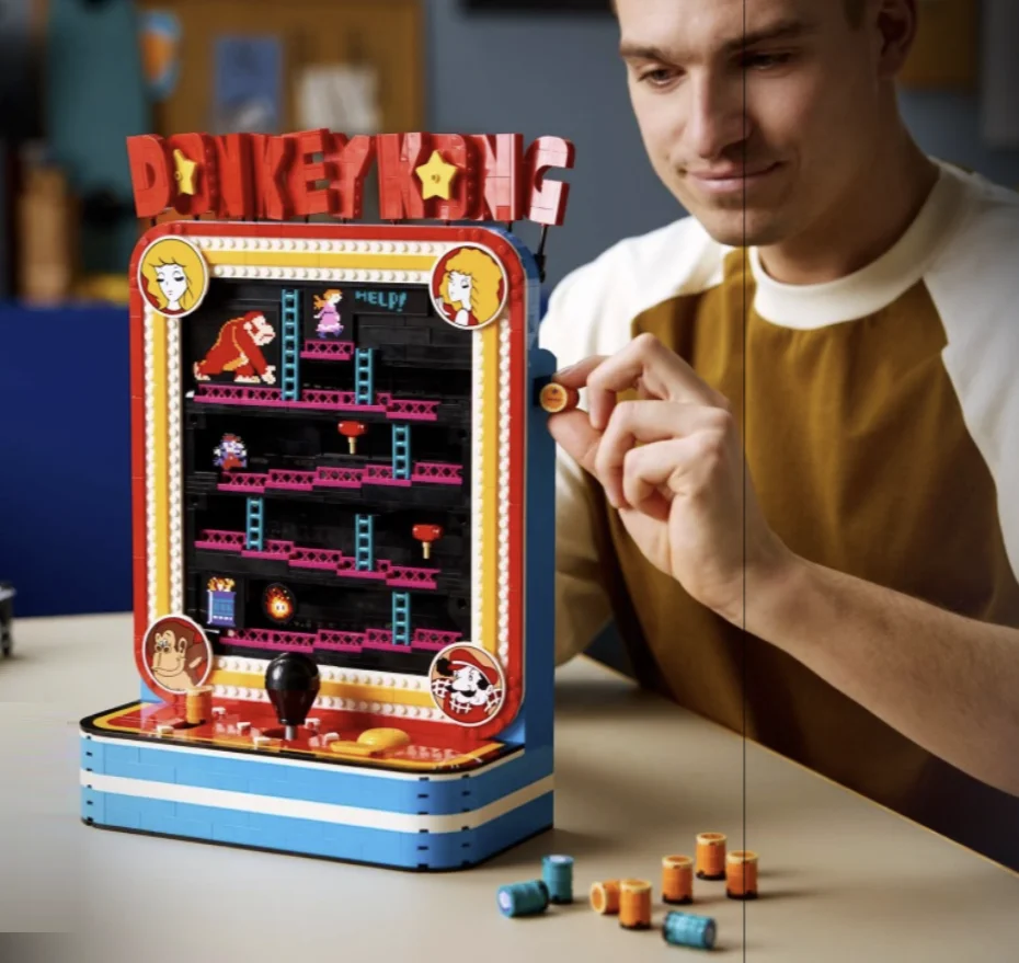 Pessoa interagindo com o set LEGO Donkey Kong Arcade enquanto movimenta um dos barris do fliperama.