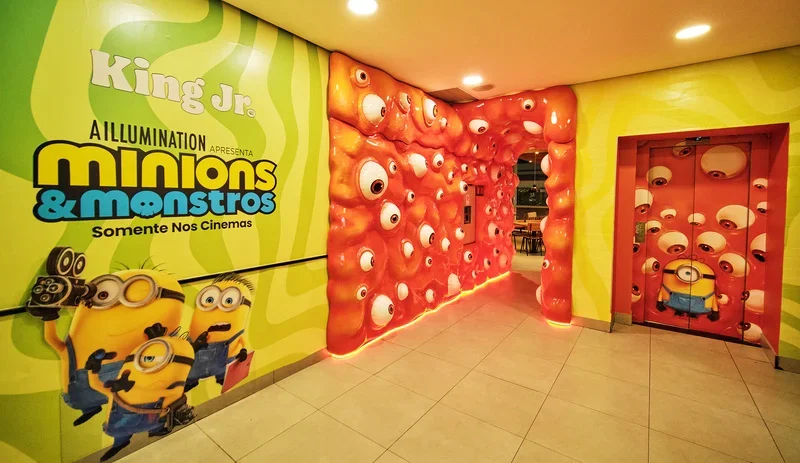 Entrada interna da loja temática do Burger King com portal cenográfico inspirado em Minions & Monstros e decoração repleta de olhos e personagens da franquia.