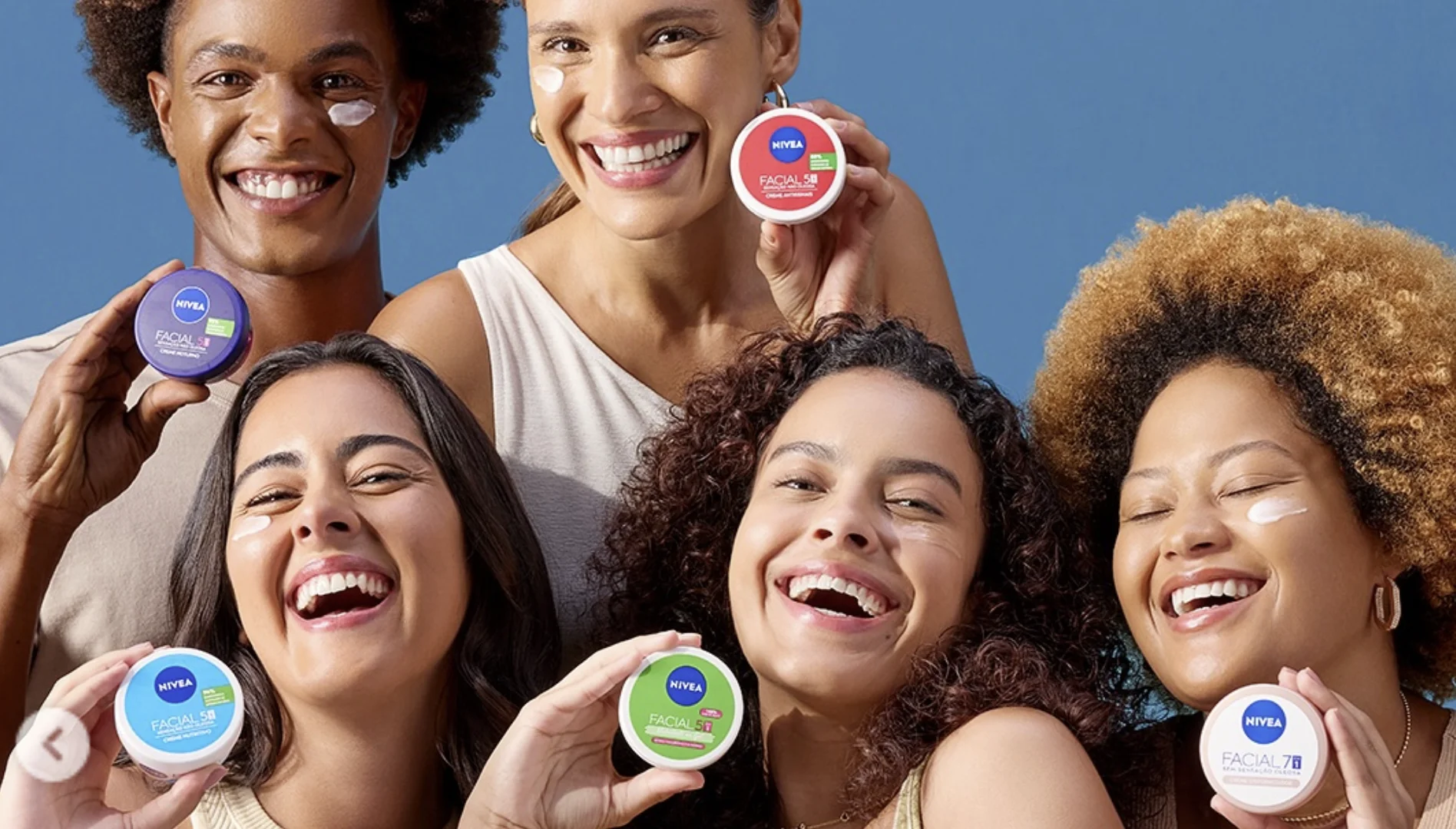 Grupo de cinco pessoas sorri enquanto exibe diferentes cremes faciais Nivea em imagem promocional da campanha.