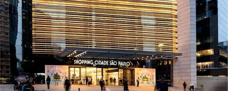 Fachada iluminada do Shopping Cidade São Paulo na Avenida Paulista durante a noite.