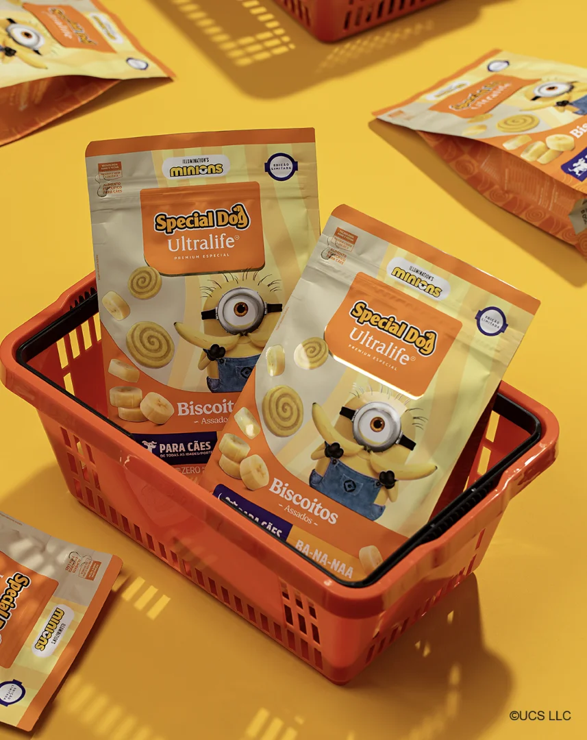 Pacotes de biscoitos Special Dog dos Minions dentro de cesta de compras em cenário amarelo promocional.