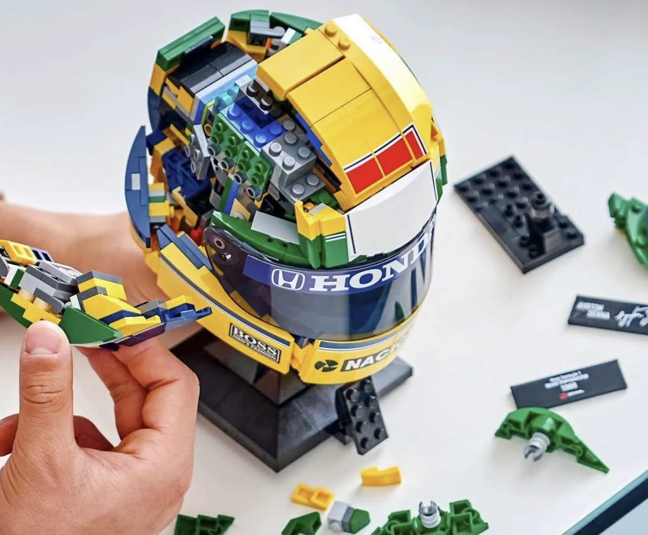 Capacete de Ayrton Senna em LEGO durante montagem com peças removidas.