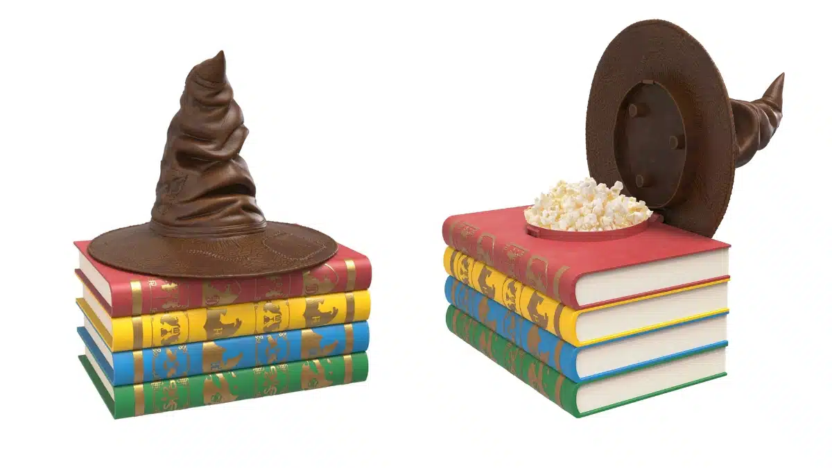Balde de pipoca de Harry Potter fechado e aberto, mostrando o compartimento interno para pipoca sobre livros coloridos.
