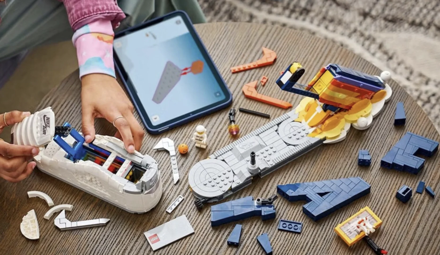 Pessoa montando o Nike Air Force 1 de LEGO sobre uma mesa.