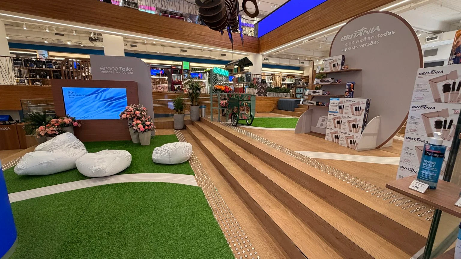 Área do Época Talks com almofadas, flores e espaços de marcas na Galeria Magalu.