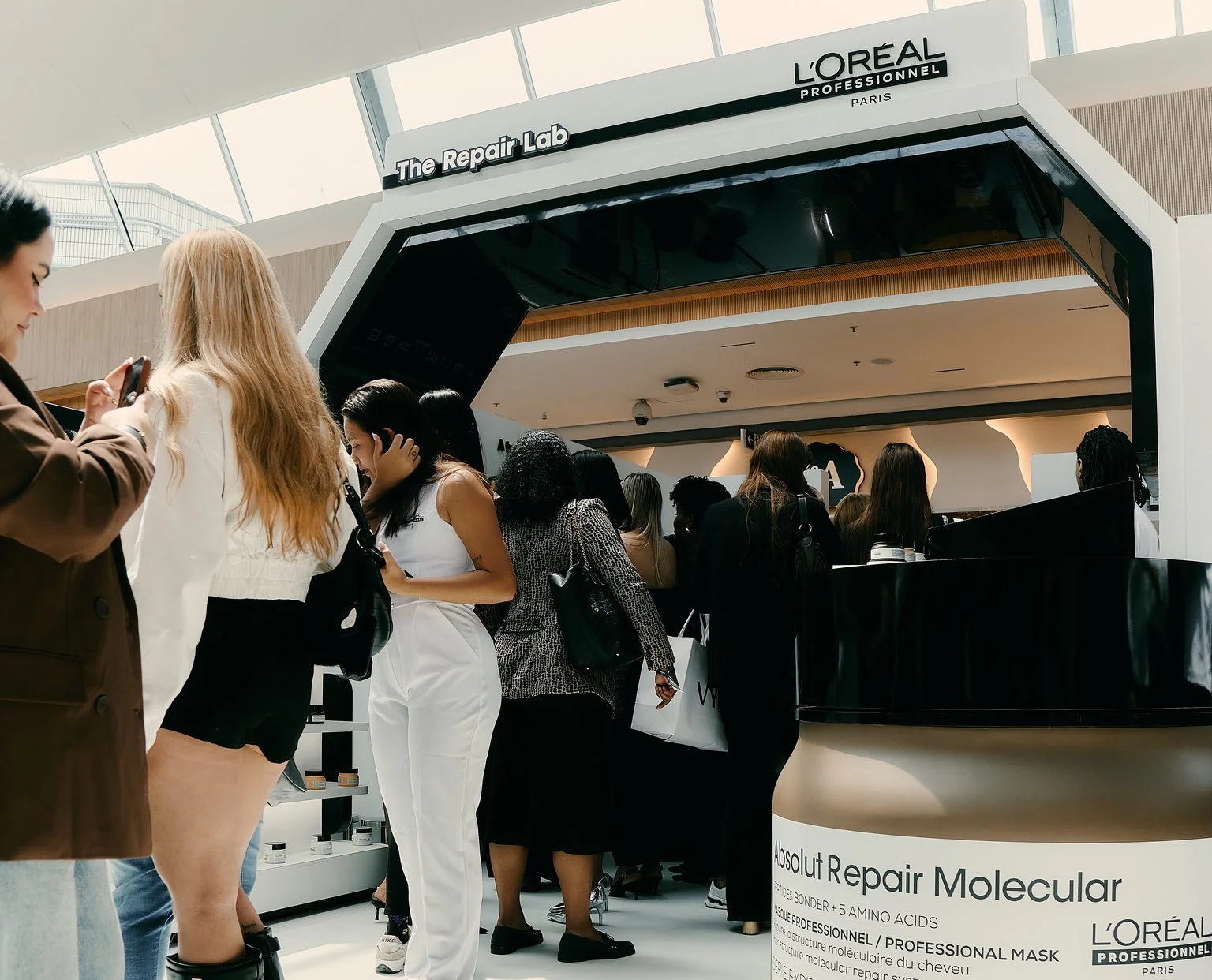 Visitantes reunidos na entrada da The Repair Lab, sob a identificação da L’Oréal Professionnel.