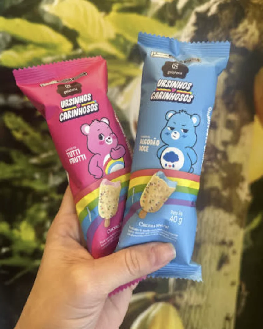 Mão segura gelatos dos Ursinhos Carinhosos da Cacau Show.
