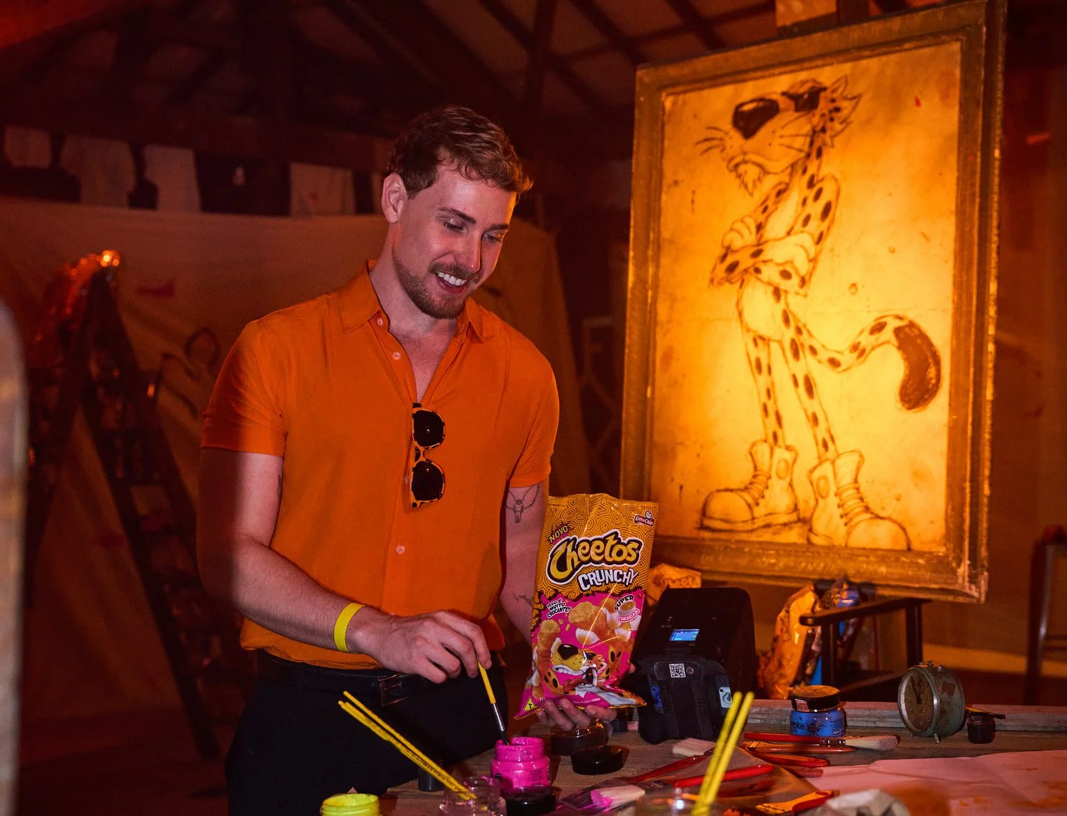 Convidado participa de atividade artística com Cheetos diante de quadro de Chester Cheetah.