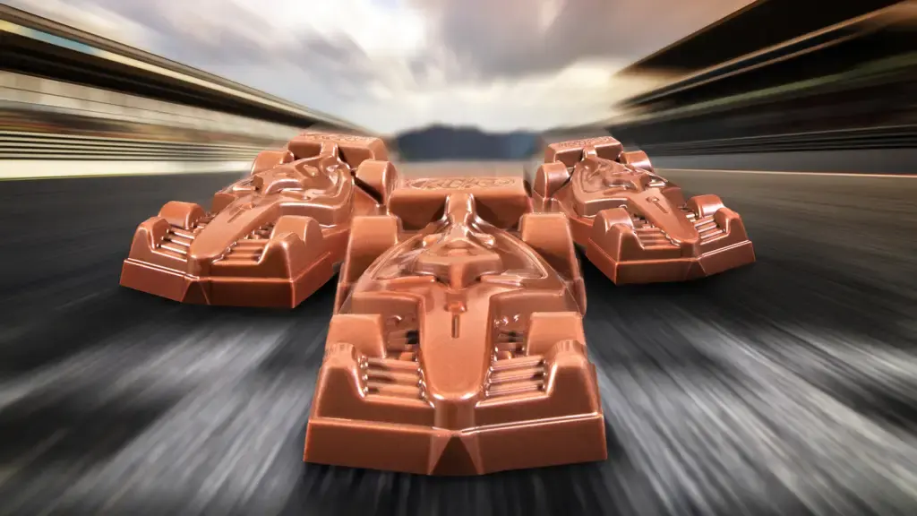 Três carrinhos de chocolate KitKat inspirados nos carros da Fórmula 1 em uma pista de corrida.