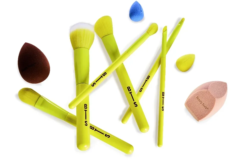 Pincéis de maquiagem amarelos e esponjas coloridas da Beauty Tools dispostos sobre fundo branco.