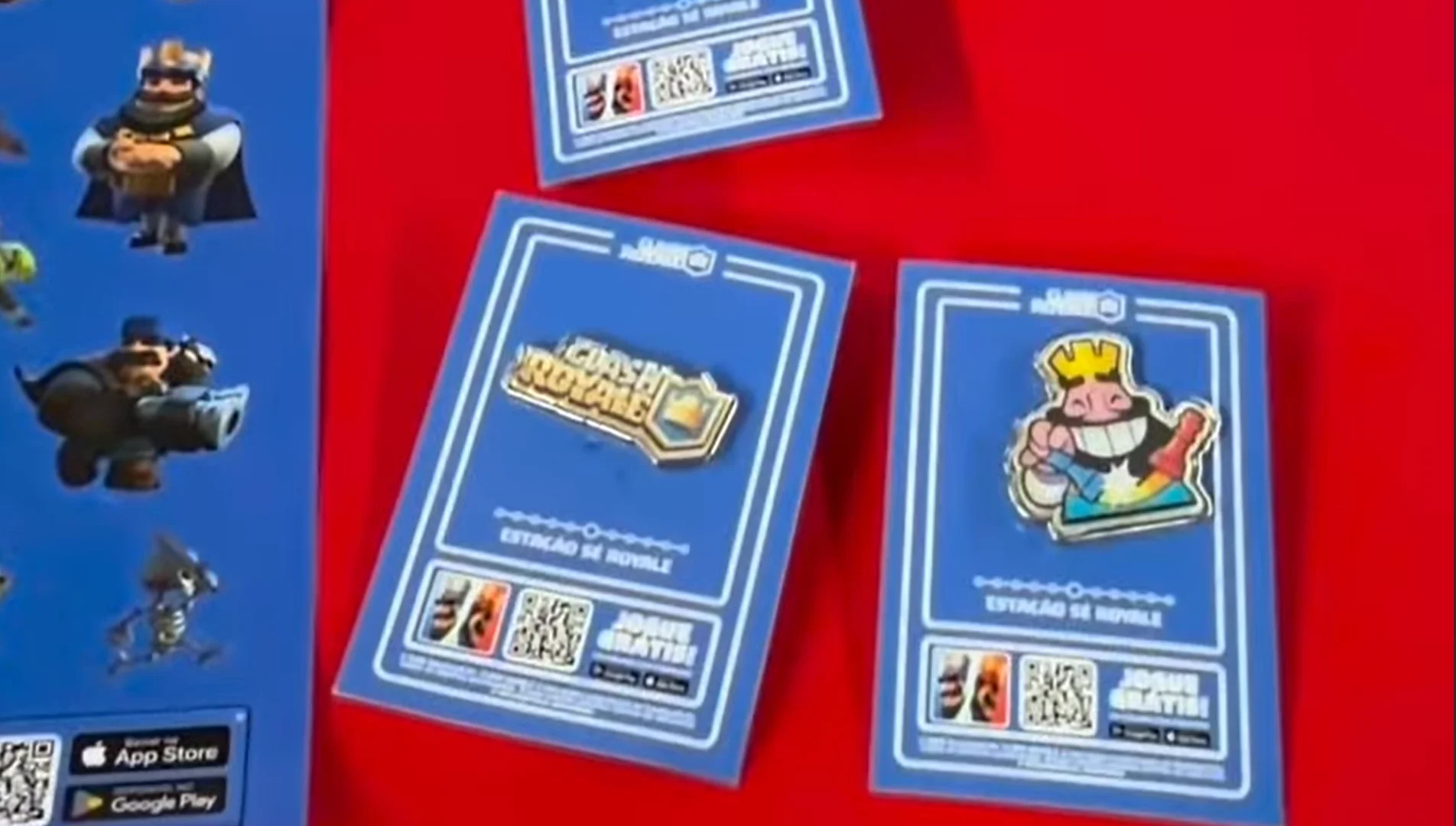 Cartelas azuis de Clash Royale com adesivos temáticos, personagens do jogo e códigos QR sobre uma mesa vermelha.