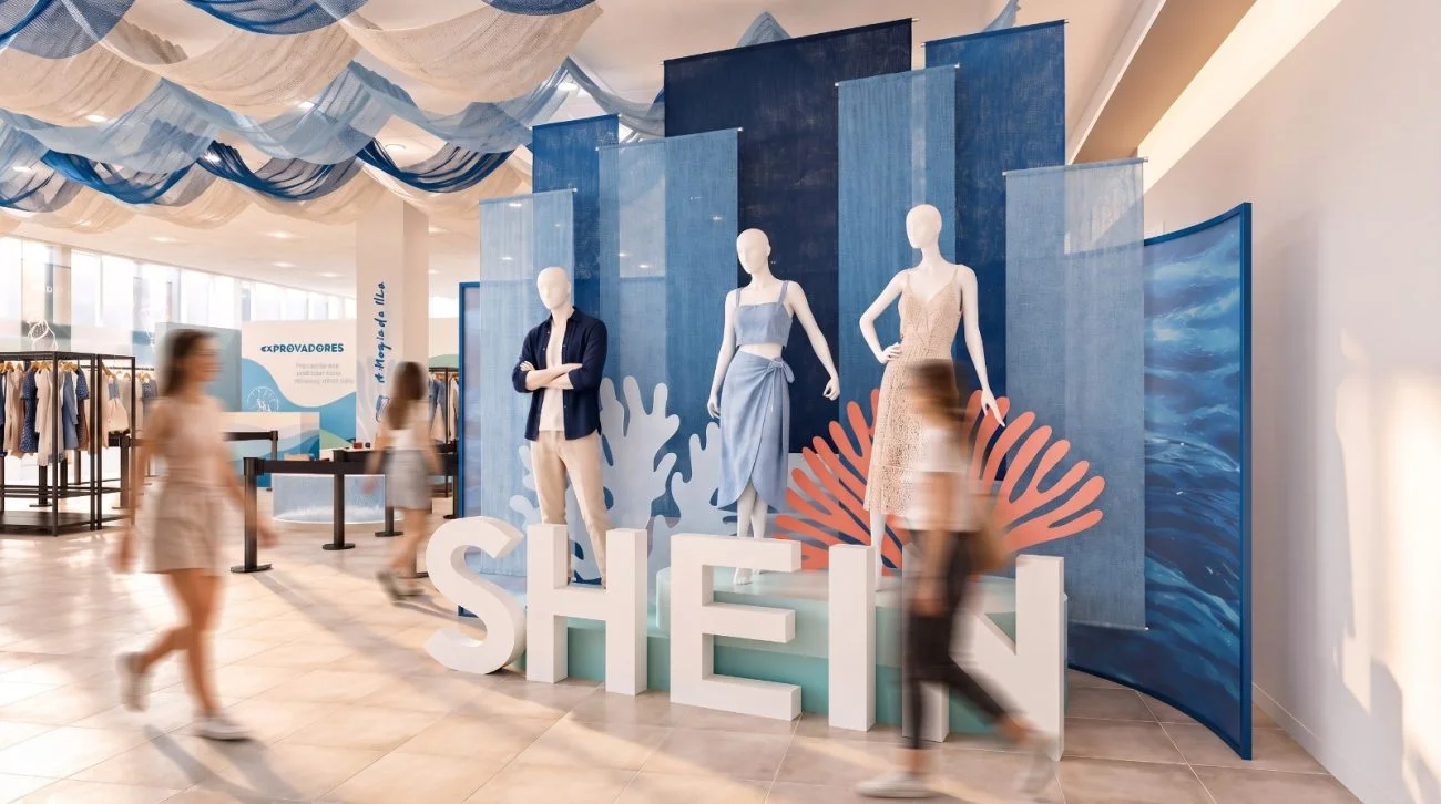 Manequins exibem roupas femininas e masculinas na loja temporária da SHEIN em Florianópolis, com painéis azuis e decoração marinha.
